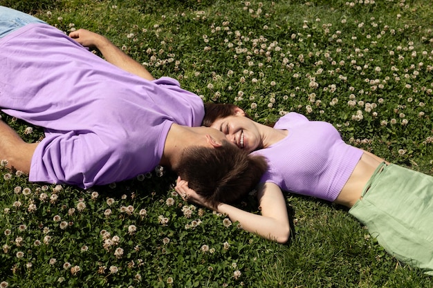 Free photo cute boyfriend and girlfriend lying on grass