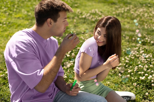 Cute boyfriend and girlfriend playing with soap bubbles