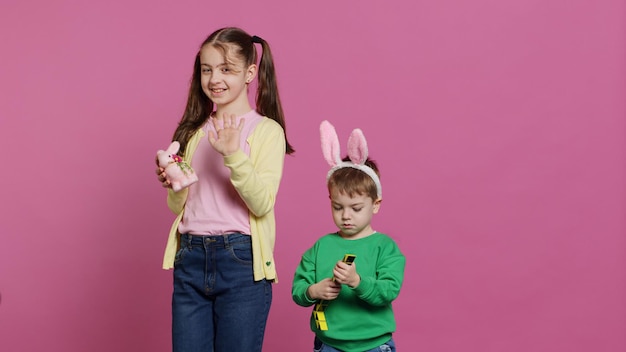 Cute brother and sister posing against pink background in studio