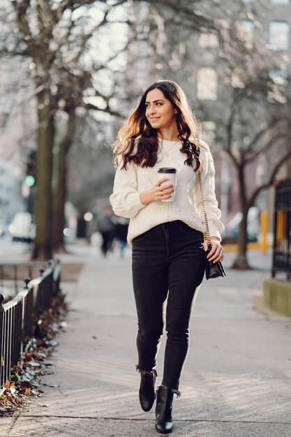 Cute brunette in a white sweater in a city