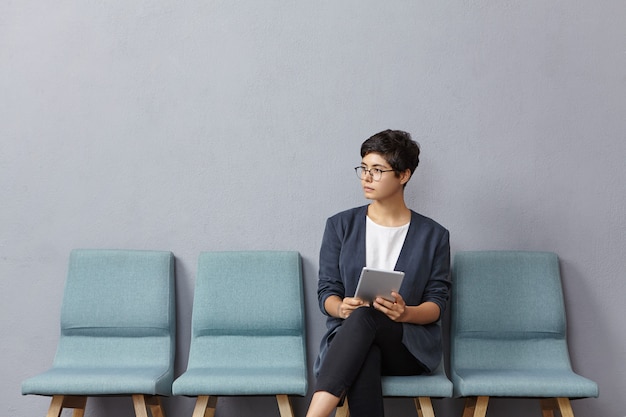 Free photo cute businesswoman looks pensively aside, waits meeting with partners