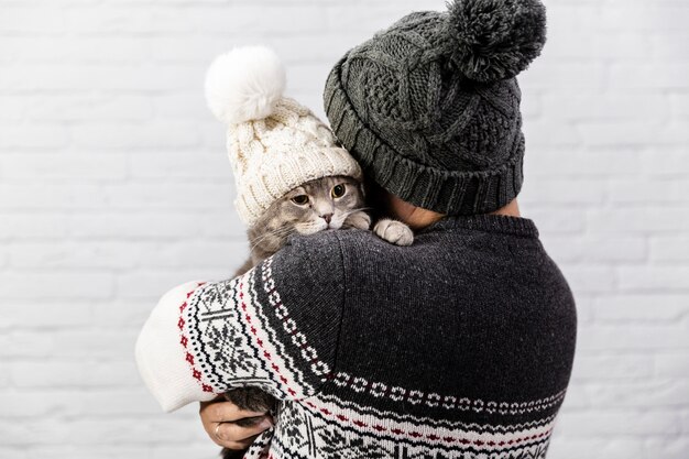 Cute cat with hat held by owner