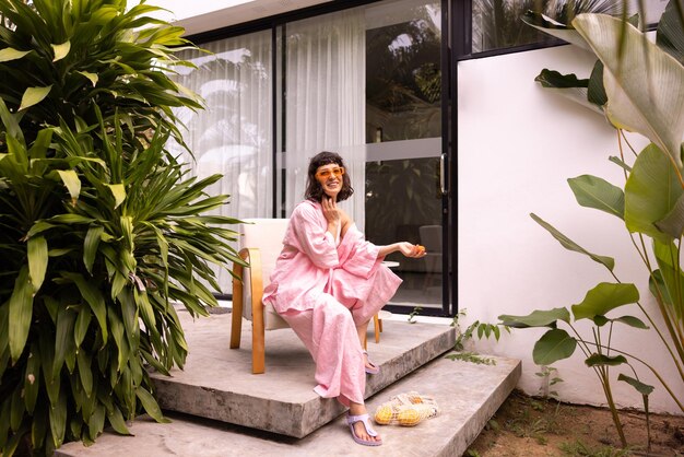 Cute caucasian young brunette girl wears pink clothes and glasses sitting on armchair warm summer day Lifestyle different emotions leisure concept