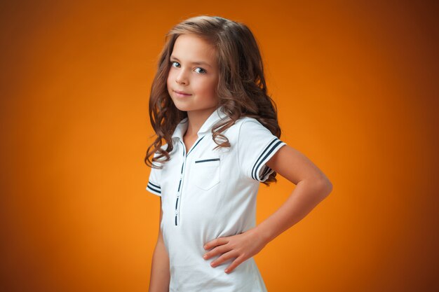 Милая веселая маленькая девочка на оранжевом фоне
