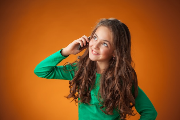 The cute cheerful little girl on orange background