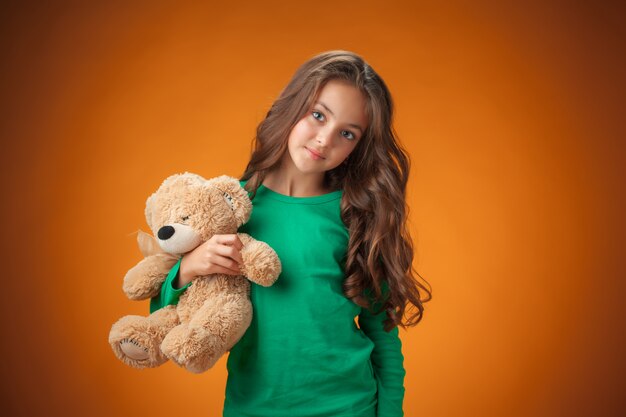 The cute cheerful little girl on orange background