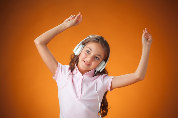 The cute cheerful little girl on orange background