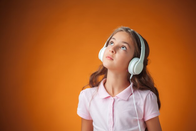 The cute cheerful little girl on orange wall