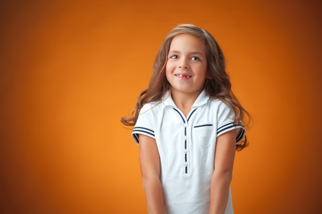милая веселая маленькая девочка на оранжевом