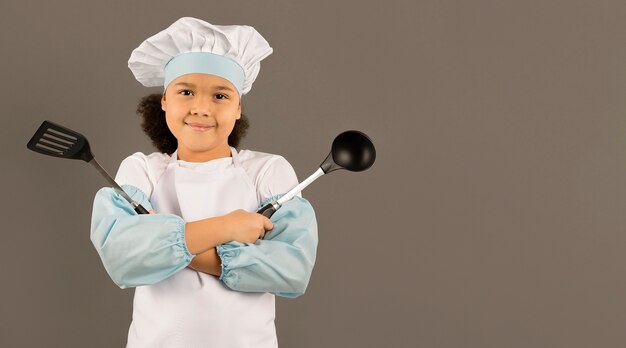 Cute chef holding cooking utensils