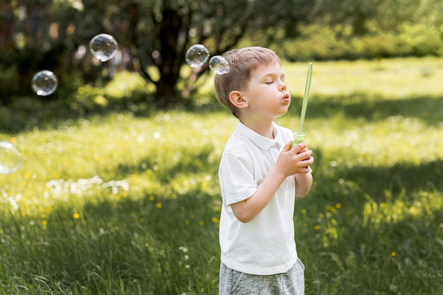 Милый ребенок пускает мыльные пузыри со своей игрушкой