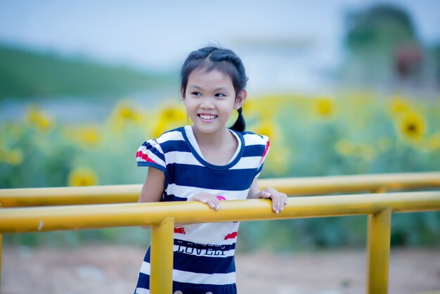 Cute child girl with sunflower in summer field