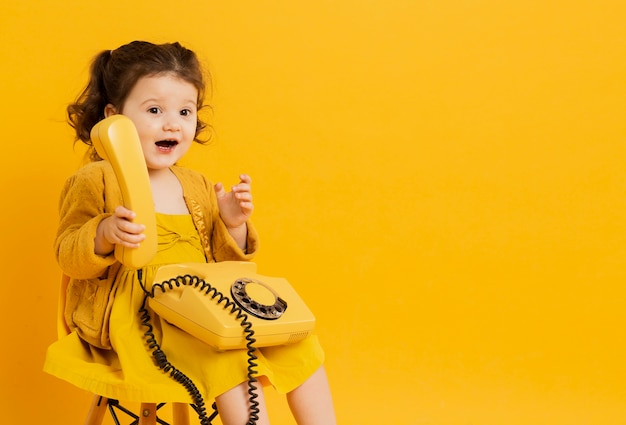 Foto gratuita telefono sveglio della tenuta del bambino mentre posando