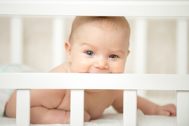 Симпатичный ребенок, интересующийся рамкой детской кроватки