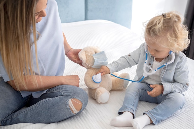 Cute child playing with toy and stethoscope at home during quarantine