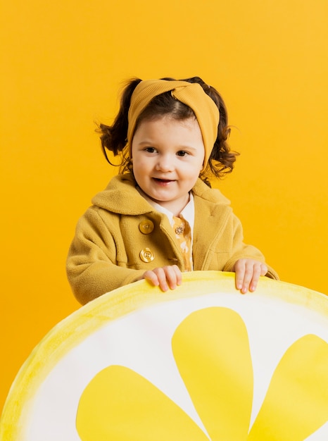Cute child posing while holding lemon slice decoration