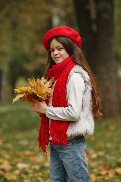 赤いベレー帽のかわいい子。エレガントな小さな女性。葉の花束を持つ子。