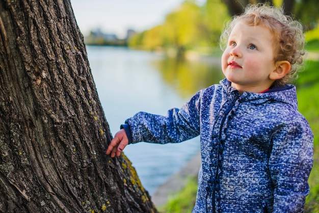 Foto gratuita bambino carino accanto a un tronco