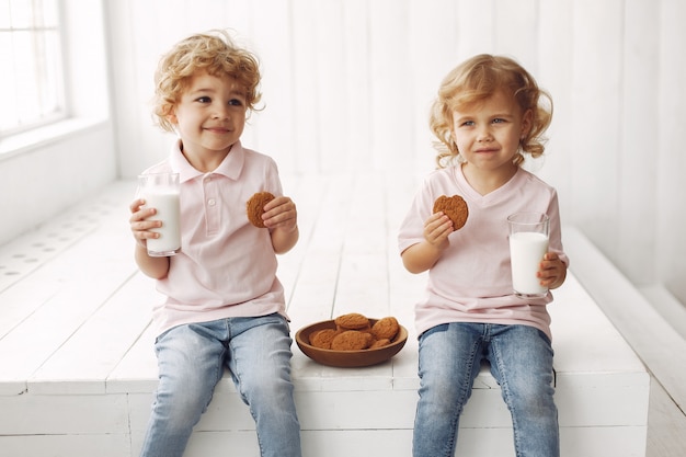 Cute children eating cookies and drinking milk