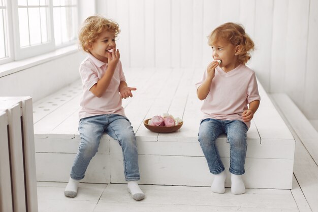 Cute children eating cookies at home