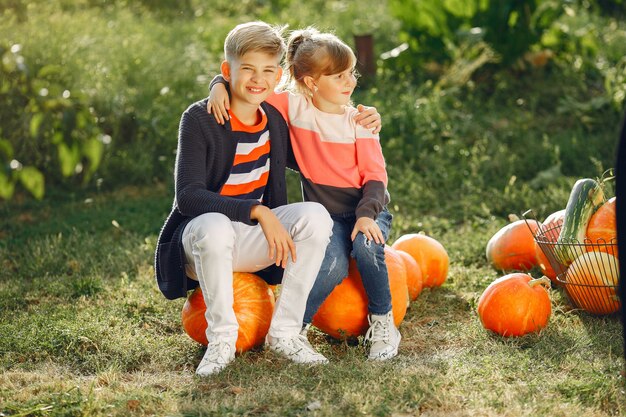 Free photo cute childresn sitting on a garden near many pumpkins