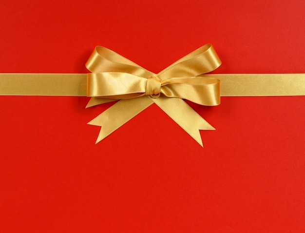 Золотой подарок лук на красном фоне бумаги