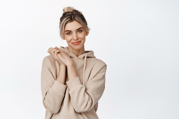 Free photo cute coquettish girl hope to achieve something clasp hands together and looking hopeful smiling at camera standing over white background