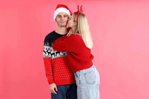 Cute couple in christmas clothes on pink background