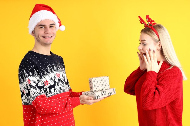 Cute couple in christmas clothes on yellow background