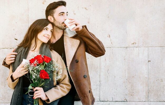 Cute couple drinking near wall