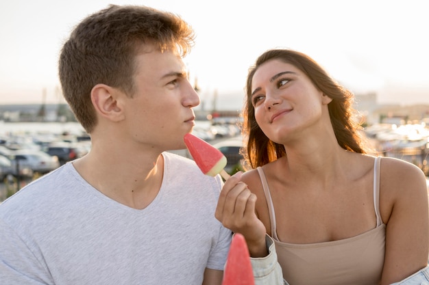 Free photo cute couple eating popsicles outdoors