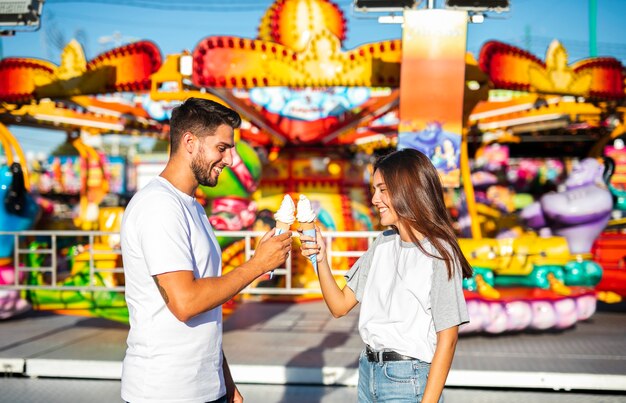 Милая пара держит мороженое на ярмарке