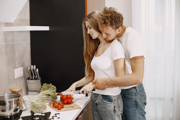 Foto gratuita coppia carina a casa. signora in una maglietta bianca. le persone preparano un'insalata.