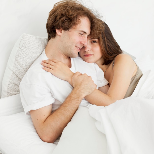침대 중간 샷에서 포옹하는 귀여운 커플