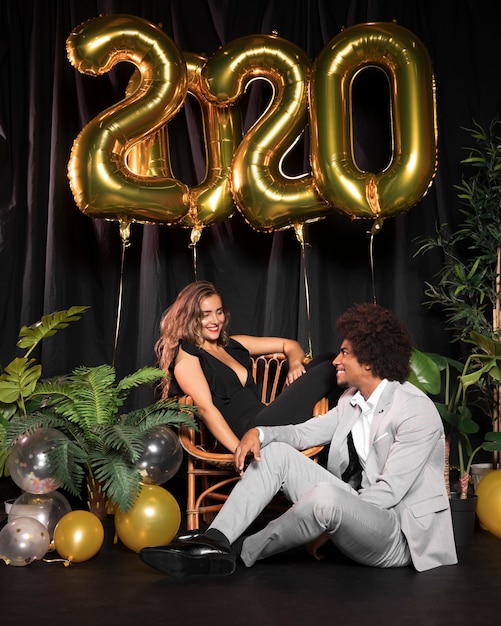 Cute couple looking at each other surrounded by balloons with 2020 new year