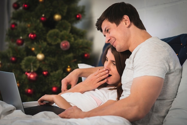 Cute couple looking at laptop in bed