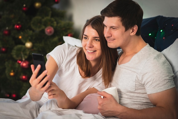 Cute couple looking at phone in bed