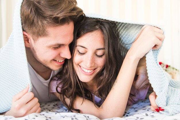 Cute couple lying under blanket