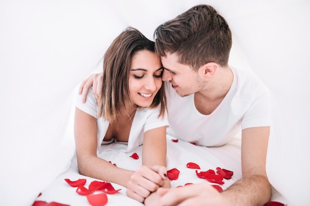 Free photo cute couple lying on rose petals