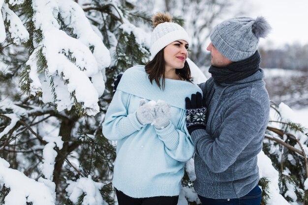 かわいいカップル、雪の多いスプルースの近く