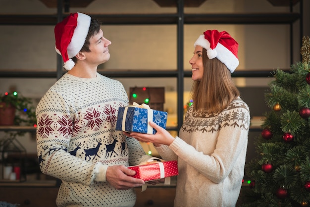 Cute couple offering each other gifts