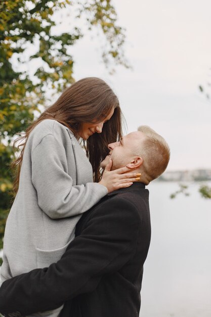 Cute couple in a park. Lady in a gray coat. People on the pier.