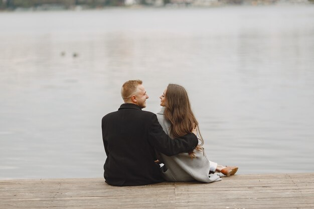 Cute couple in a park. Lady in a gray coat. People on the pier.