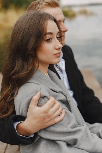 Cute couple in a park. Lady in a gray coat. People on the pier.