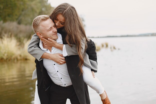 Cute couple in a park. Lady in a gray coat. People on the pier.