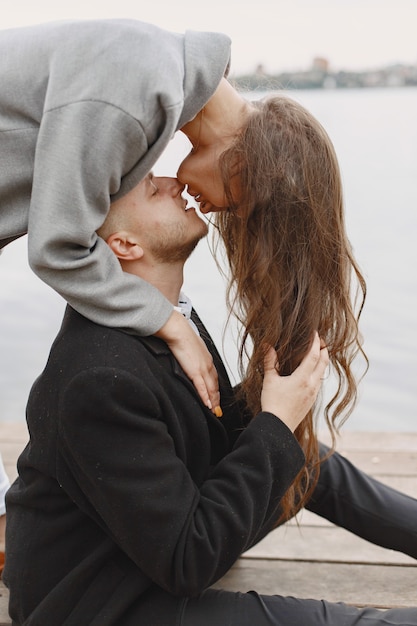 Free photo cute couple in a park. lady in a gray coat. people on the pier.