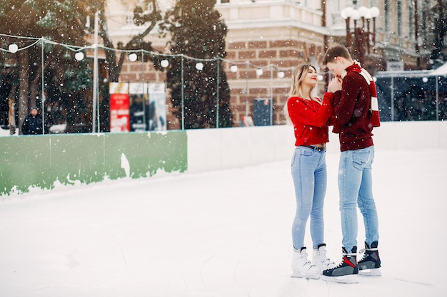 Free photo cute couple in a red sweaters having fun in a ice arena