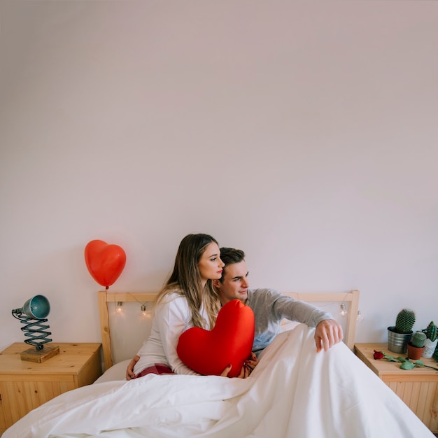 Cute couple sitting on bed with heart