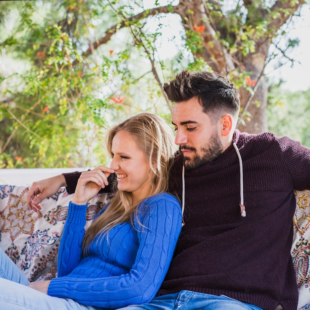 Cute couple sitting on sofa near greenery