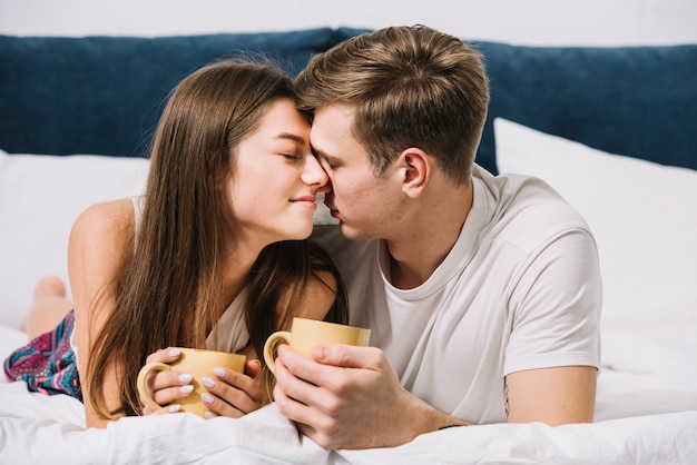 Free photo cute couple with coffee on bed